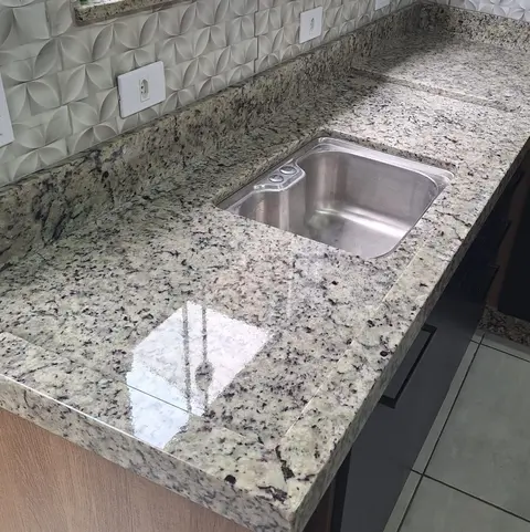 Bancada em granito claro polido com cuba de inox embutida e frontão