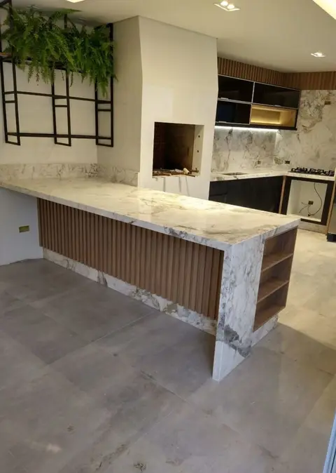 Área gourmet com balcão em pedra de veios e churrasqueira