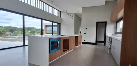 Ilha de tampo branco em cozinha integrada, com vista para a área externa